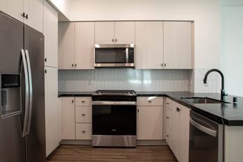 A modern kitchen with white cabinets and stainless steel appliances.